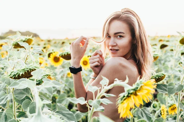 Ein junges Mädchen oben ohne steht in Sonnenblumen — Stockfoto