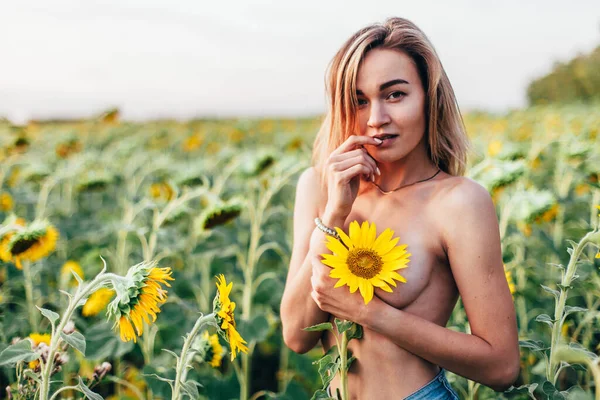 Une jeune fille seins nus se tient dans des tournesols — Photo