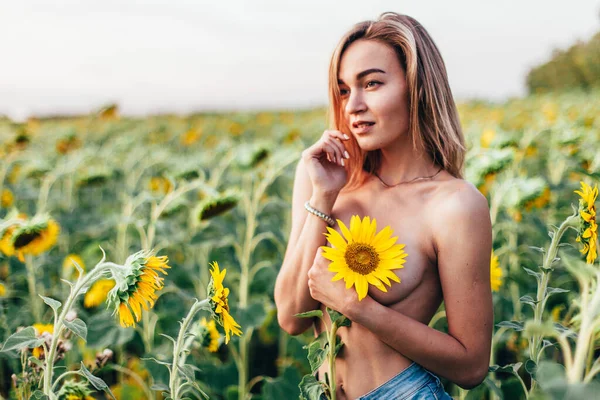 Ein junges Mädchen oben ohne steht in Sonnenblumen — Stockfoto
