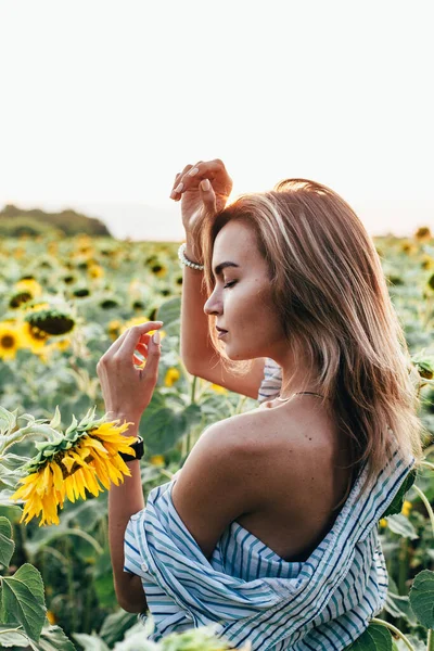 Tişörtlü genç bir kız ayçiçeklerinin içinde duruyor. — Stok fotoğraf