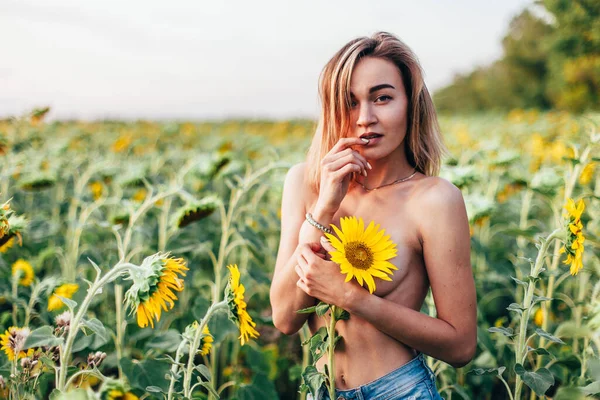 Mladá dívka nahoře bez stojí na slunečnicích — Stock fotografie