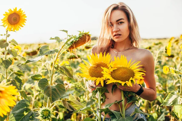 Genç üstsüz bir kız ayçiçeklerinde duruyor. — Stok fotoğraf