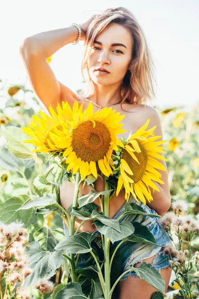 Une jeune fille seins nus se tient dans des tournesols — Photo