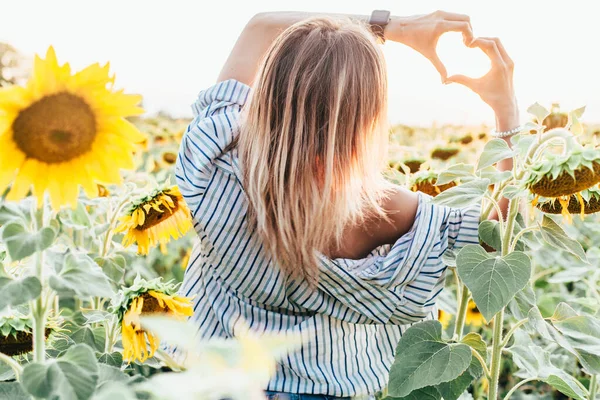 一个穿着衬衫的小女孩站在向日葵上 — 图库照片