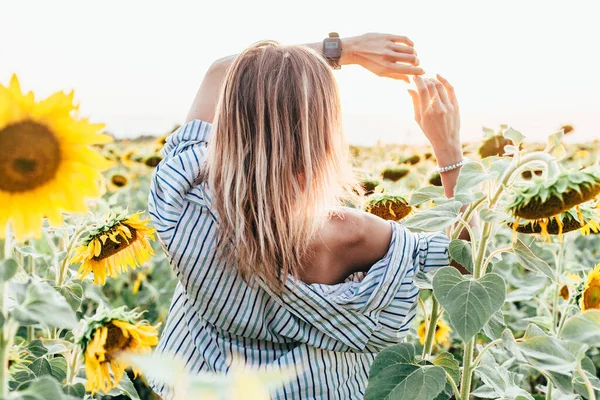 Uma jovem com uma camisa fica em girassóis — Fotografia de Stock