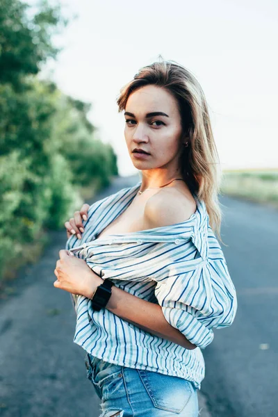 Beautiful girl hitchhiking on the track in a mans shirt — Stock Photo, Image