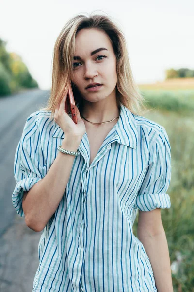 Beautiful girl hitchhiking on the track in a mans shirt — Stock Photo, Image