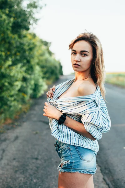 Mooi meisje liftend op de baan in een mannenshirt — Stockfoto