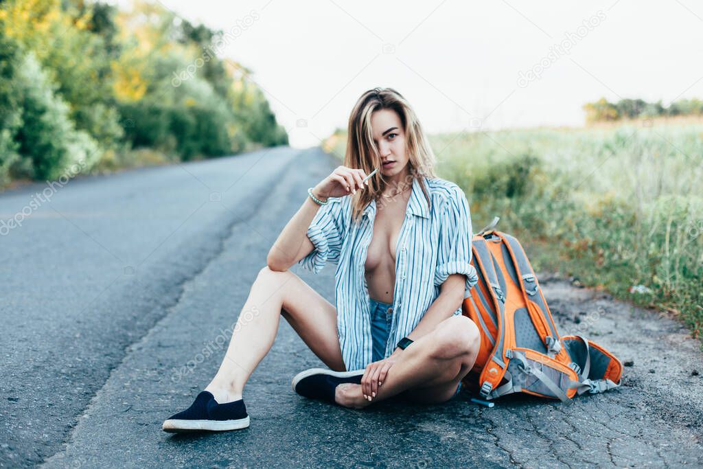 Beautiful girl hitchhiking on the track in a mans shirt