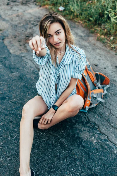 Beautiful girl hitchhiking on the track in a mans shirt — Stock Photo, Image