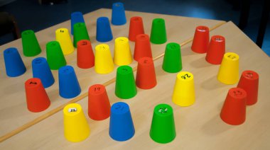 Plastik renkli numaralandırılmış bardaklar oyun için hazırlanan bir masada baş aşağı çevrilmiş, takım oluşturma