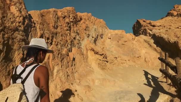 女の子が歩いてスローモーションをヒルズのサハラでサハラ砂漠の単独で歩いている女の子のショットを安定化 アフリカの砂漠を冒険します — ストック動画