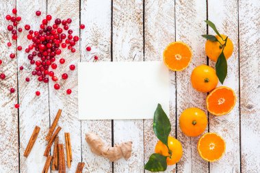 Boş bir kağıt yaprağına ve mandalina, tarçın ve kızılcık beyaz tahta masada. Noel pişirme. Üstten Görünüm