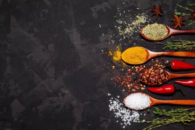 Kaşık üstten görünüm koyu siyah arka plan üzerinde renkli baharat. Yemek ve mutfak malzemeleri.