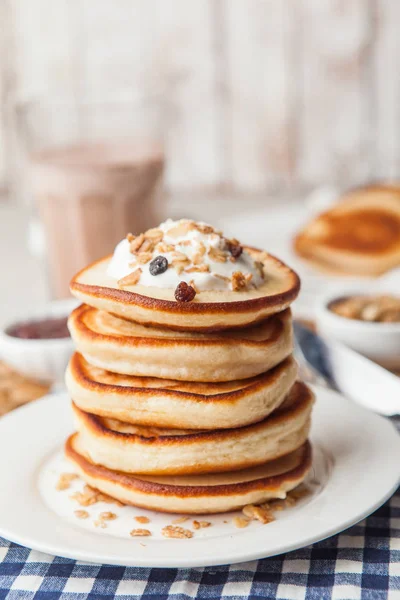 Krem ve granola ile beyaz bir tabak krep yığını. Maslenit