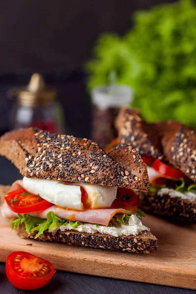 Sandwich mit Schinken und pochiertem Ei auf Holzbrett — Stockfoto