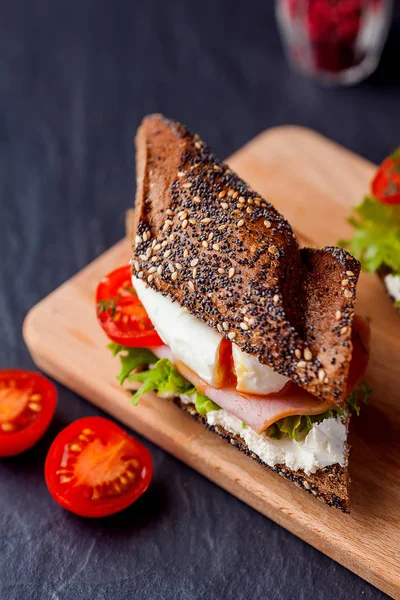 Sandwich mit Schinken, pochiertem Ei und frischen Tomaten auf Wildschweinen — Stockfoto