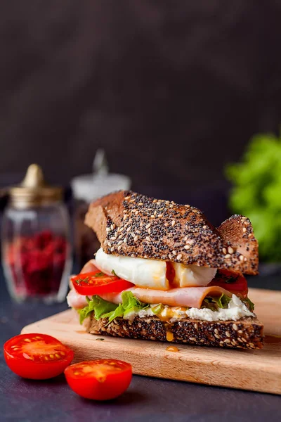Сэндвич с ветчиной, яичницей и свежими помидорами на кабане — стоковое фото