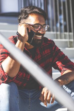 Yakışıklı genç adam, dışarıda. Hintli adam cep telefonuyla konuşuyor..