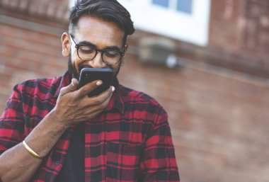 Yakışıklı genç adam, dışarıda. Hintli adam cep telefonundan sesli mesaj gönderiyor..
