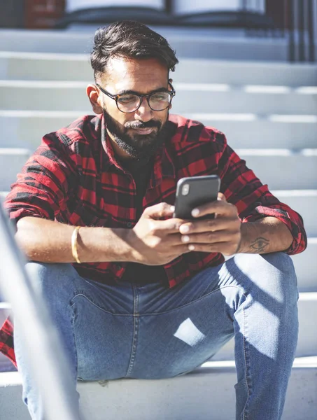 Handsome young man, outdoor.Indian man is texting a message on a cell phone.