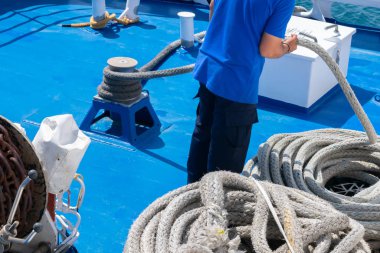 Gemideki denizci limanda demirleme yapıyor. Halat bir spiral veya halka dizisi içinde kıvrılma ve yara