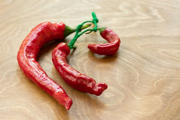 Dried red hot chili pepper as spicy flavoring for meal. A group of bright red Thai Chili peppers with green stem on wooden background. Hot and spicy ingredients for making sauces or curry paste in Asian style cuisine.