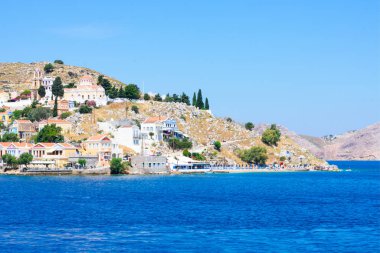 Akdeniz 'in kayalık sahillerinde güneşli yaz günlerinde Simy Yunan adasında bir sürü küçük renkli ev, egzotik adalarda turizm