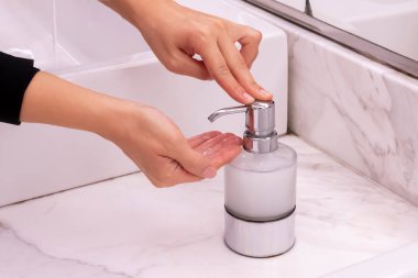 Genç kız, su dolabındaki musluktan akan suyun altında aynayla ellerini yıkıyor. Temizlik ve hijyen kavramı