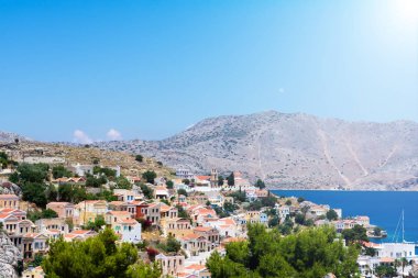 Küçük renkli evlerin resimli görüntüsü kayaların üzerinde, Akdeniz kıyısındaki yeşil ağaçlar güneşli yaz günlerinde güneş ışınları, egzotik adalarda tatil