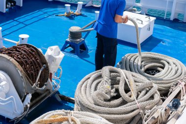 Gemideki denizci limanda demirleme yapıyor. Halat bir spiral veya halka dizisi içinde kıvrılma ve yara