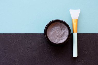 Yüz ve vücut için açık gri çamur maskesi kavanozu naneli ve siyah arka planda yumuşak fırçalı. Yüz bakımı ve tedavide kullanılan ev yapımı organik ürünler..