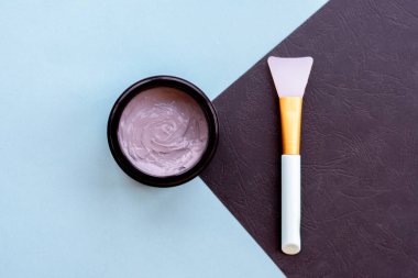 Yüz ve vücut için açık gri çamur maskesi kavanozu naneli ve siyah arka planda yumuşak fırçalı. Yüz bakımı ve tedavide kullanılan ev yapımı organik ürünler..