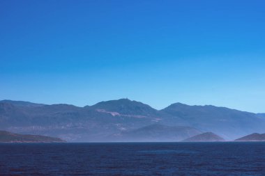 Sis içindeki dağlarla deniz manzarasından yapılmış kopya alanı ile donatılmış arkaplan 