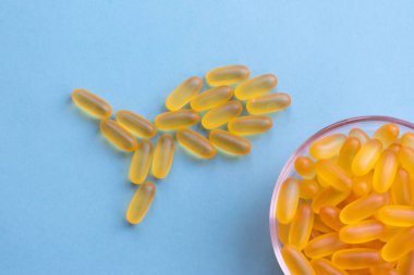 Omega 3, balık şeklinde çiğnenebilir jöle hapları. Sarı balık yağlı bir sürü kapsül mavi arka planda yatıyor. Sağlık desteği ve tedavi konsepti. Biyolojik olarak aktif katkı maddeleri. 
