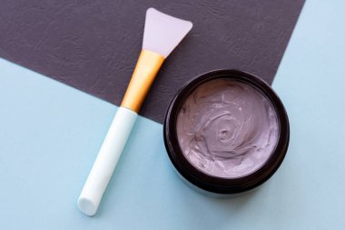 Yüz ve vücut için açık gri çamur maskesi kavanozu naneli ve siyah arka planda yumuşak fırçalı. Yüz bakımı ve tedavide kullanılan ev yapımı organik ürünler..