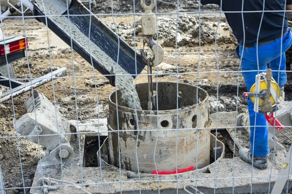 workers handling massive cement pump tube and pouring fresh conc