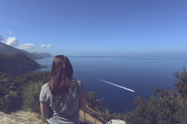 Genç bir turist kadının okyanusa bakışının arkası.