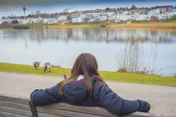 아름다운 여인 이 호수 근처의 난치에 앉아 — 스톡 사진