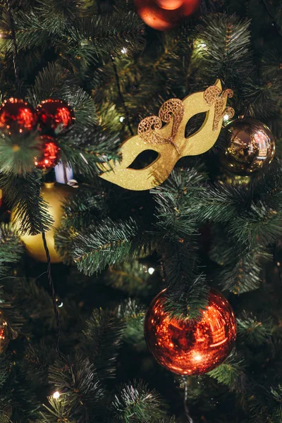 Icicle'ı ışıklar diğer kırmızı ve sarı parlak baubles ile Noel ağacı üzerinde bir Noel ağacı oyuncak gibi altın karnaval maskesi