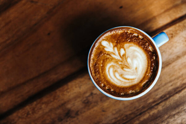 Cappuccino in a blue mug on a wooden table. Coffee view from above