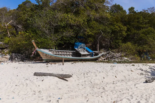 A broken boat stands on the sand. Boat by the sea. Fishing boat washed ashore