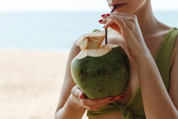 Flickan med kokosnöten på stranden. Flicka dricker kokosmjölk på stranden Royaltyfria Stockfoton