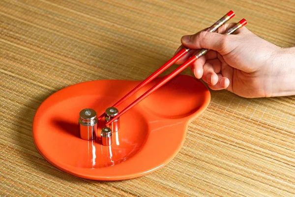 Ellerinde çubuklar var. Seramik sofra takımı. Çin yemek çubukları. Modern minimalist yemekler. Renkli seramik tabaklar. Ölçekler için metal ağırlıklar