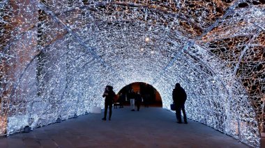 Cenova, İtalya - 11 / 19 / 2019: Kırmızı beyaz ve turuncu renkli kurşun ışık galerisi. Düşük açı. İnsanlar Noel süslemelerinin tadını çıkarıyor..