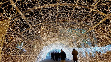 Cenova, İtalya - 11 / 19 / 2019: Kırmızı beyaz ve turuncu renkli kurşun ışık galerisi. Düşük açı. İnsanlar Noel süslemelerinin tadını çıkarıyor..