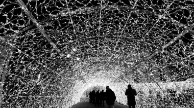 Cenova, İtalya - 11 / 19 / 2019: Kırmızı beyaz ve turuncu renkli kurşun ışık galerisi. Düşük açı. İnsanlar Noel süslemelerinin tadını çıkarıyor..