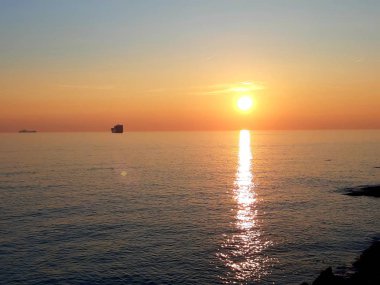 Cenova, İtalya - 11 / 25 / 2019: Cenova Denizi üzerinde kış günbatımının muhteşem bir başlığı güzel kırmızı ve mavi gökyüzü, arka planda inanılmaz bulutlar ve denizin üzerinde eski kayalar.