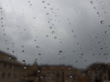 Cenova, İtalya - 11 / 28 / 2019: İnanılmaz renkli bir gökyüzü ve bir parça güneş ışığı ile çok şiddetli bir yağmurdan sonra pencerenin üzerindeki su damlasının inanılmaz bir başlığı. Takasın makro fotoğrafçılığı.