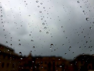 Cenova, İtalya - 11 / 28 / 2019: İnanılmaz renkli bir gökyüzü ve bir parça güneş ışığı ile çok şiddetli bir yağmurdan sonra pencerenin üzerindeki su damlasının inanılmaz bir başlığı. Takasın makro fotoğrafçılığı.